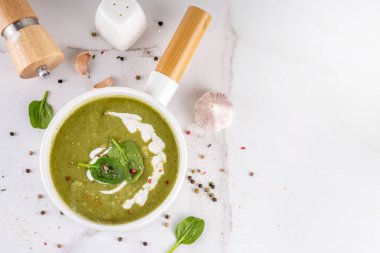Lezzetli yeşil ıspanak kremalı çorba, kremalı ve taze ıspanak yapraklı. Lezzetli kremalı çorba, baharatlar ve beyaz masa arkasında zeytinyağı. Sağlıklı diyet bahar vejetaryen yemek tarifi