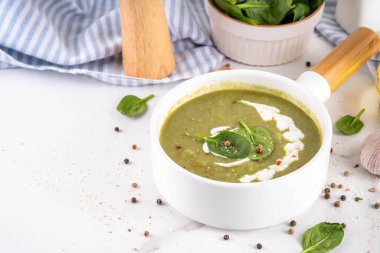 Lezzetli yeşil ıspanak kremalı çorba, kremalı ve taze ıspanak yapraklı. Lezzetli kremalı çorba, baharatlar ve beyaz masa arkasında zeytinyağı. Sağlıklı diyet bahar vejetaryen yemek tarifi