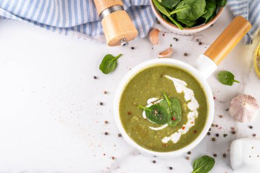 Lezzetli yeşil ıspanak kremalı çorba, kremalı ve taze ıspanak yapraklı. Lezzetli kremalı çorba, baharatlar ve beyaz masa arkasında zeytinyağı. Sağlıklı diyet bahar vejetaryen yemek tarifi
