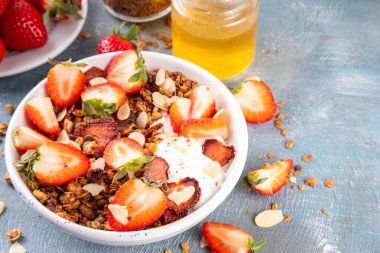 Sağlıklı yaz meyveli kahvaltı kasesi granola, kremalı Yunan yoğurdu ve çilekli. Lezzetli dengeli atıştırmalık, kilo kaybı, sağlıklı sabah yemeği tarifi.