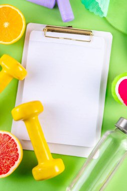 Fitness and healthy food lifestyle concept. Dumbbells, healthy full of vitamins fruits -apple, grapefruit, orange, with water bottle, jump rope on colorful bright background, top view copy space