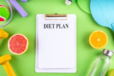 Fitness ve sağlıklı gıda yaşam tarzı konsepti. Dambıllar, vitamin dolu sağlıklı meyveler elma, greyfurt, portakal, su şişesi, renkli parlak arka planda ip atlama, üst görünüm kopyalama alanı