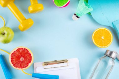 Fitness and healthy food lifestyle concept. Dumbbells, healthy full of vitamins fruits -apple, grapefruit, orange, with water bottle, jump rope on colorful bright background, top view copy space