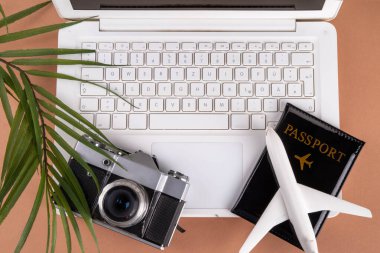 Yaz işi ve seyahat geçmişi, evraklı beyaz dizüstü bilgisayar, bilet, uçak ve fotoğraf makinesi güneşli plaj renklerinde bej arka plan görüntüleme alanı