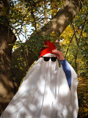 Kırmızı şapkalı ve güneş gözlüklü havalı hayalet, komik Cadılar Bayramı 2025 havası, modern sosyal medya konsepti. Yüksek kalite fotoğraf