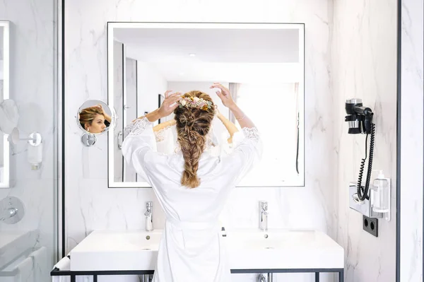 Beautiful woman putting on makeup in the mirror