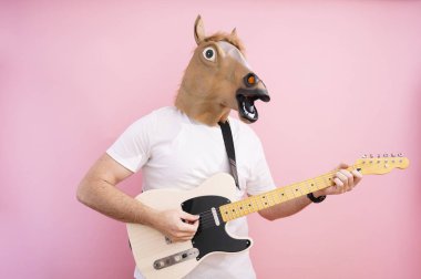 At maskeli bir adam elektro gitar çalıyor.