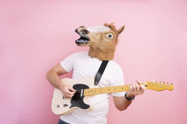 At maskeli bir adam elektro gitar çalıyor.