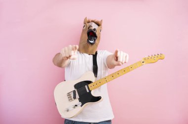 At maskeli bir adam elektro gitar çalıyor.