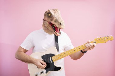 Kertenkele maskeli bir adam elektro gitar çalıyor.