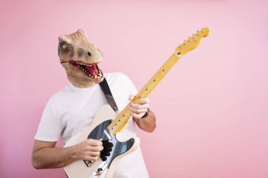 Kertenkele maskeli bir adam elektro gitar çalıyor.