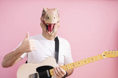 Kertenkele maskeli ve elektro gitarlı bir adam baş parmağını gösteriyor.