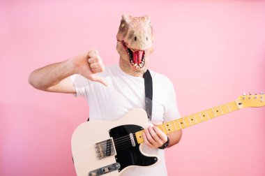Kertenkele maskeli ve elektro gitarlı bir adam baş parmağını aşağı gösteriyor.