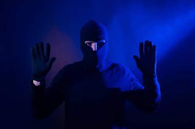 Kafkas hırsızı, elleri havada. Polis ışıklarını içerir.