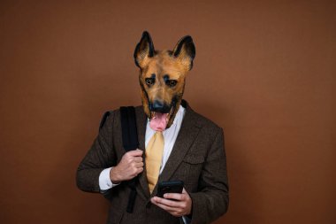 Lateks köpek kafası maskeli ve akıllı telefonlu bir adam.