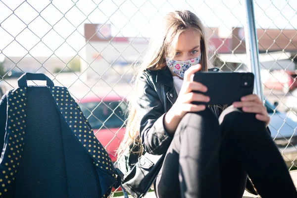Estudante Menina Sentada Porta Escola Usando Telefone Inteligente Com Máscara — Fotografia de Stock