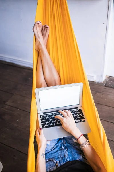 Digital nomad woman who works on a hammock hanging in a cabin in the jungle