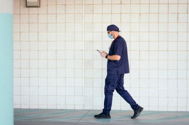 Doktor hastane dışında akıllı telefon kullanarak yürüyor.