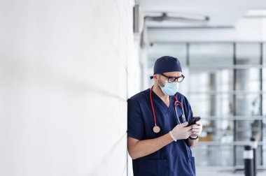 Hastanenin dışındaki doktor akıllı telefon kullanıyor.