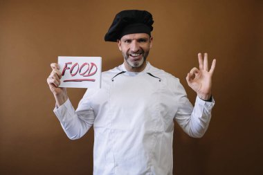 Şef elinde yemek yazan bir tabela tutuyor.