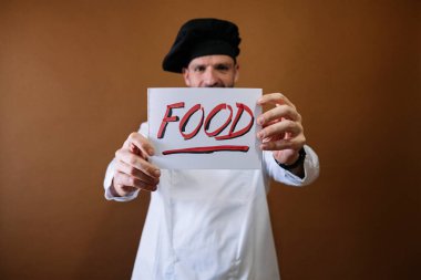 Şef elinde yemek yazan bir tabela tutuyor.