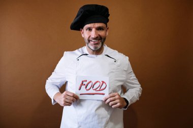 Şef elinde yemek yazan bir tabela tutuyor.