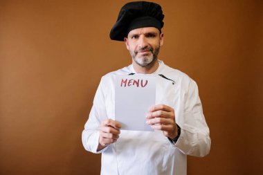 Şef elinde menü yazan bir tabela tutuyor.