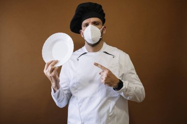 Maskeli ve boş tabağı olan bir erkek şef.