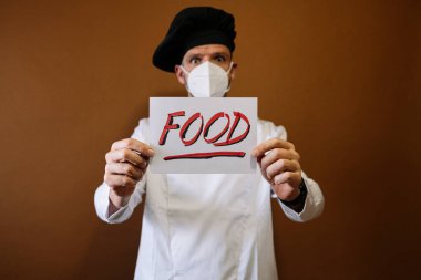 Yüzü maskeli aşçı ve üzerinde yemek yazan bir tabela