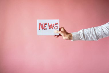 Muhabirin elinde pembe arkaplanlı haber bülteni