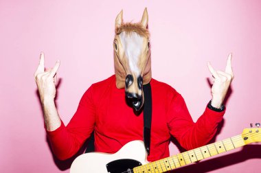 At maskeli bir adam elektro gitar çalıyor.