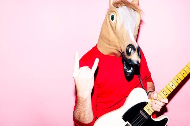 At maskeli bir adam elektro gitar çalıyor.