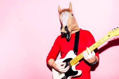 At maskeli bir adam elektro gitar çalıyor.