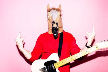 At maskeli bir adam elektro gitar çalıyor.