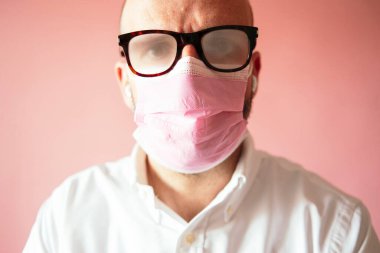 Man with foggy glasses because of the pink mask clipart