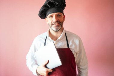 Pembe arka planda dizüstü bilgisayarı olan aşçı.