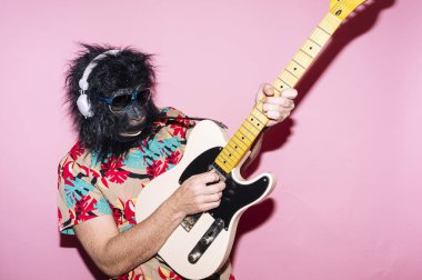Goril maskeli bir adam elektro gitar çalıyor.