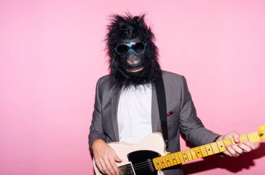 Goril maskeli bir adam elektro gitar çalıyor.
