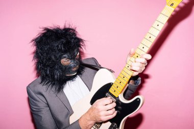 Goril maskeli bir adam elektro gitar çalıyor.