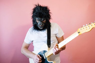 Goril maskeli bir adam elektro gitar çalıyor.
