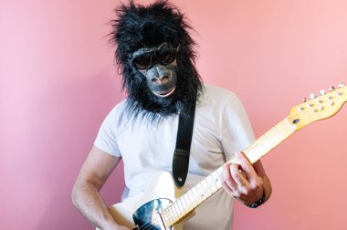 Goril maskeli bir adam elektro gitar çalıyor.