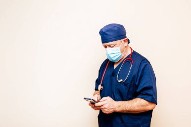 Usta doktor bej arka planda akıllı telefon kullanıyor.