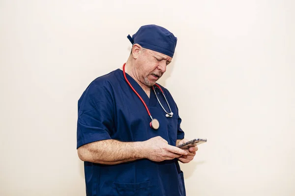 Veteran doctor using smart phone with beige background