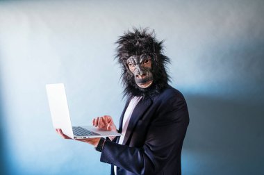 Dizüstü bilgisayar kullanan goril maskeli adam.