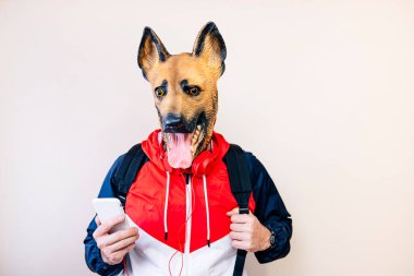 Lateks köpek kafası maskeli ve akıllı telefonlu bir adam.