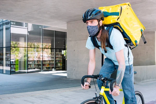 Food delivery service by delivery service. Cyclist with mask for safety.