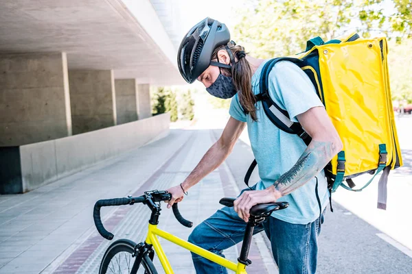 Food delivery service by delivery service. Cyclist with mask for safety.