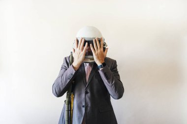 Astronot kasklı bir iş adamı elleriyle yüzünü kapatıyor.