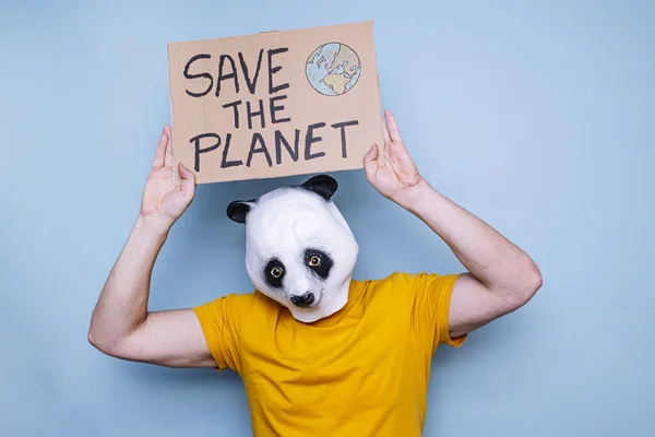 Man with panda bear head holding a cardboard sign that says SAVE THE PLANET