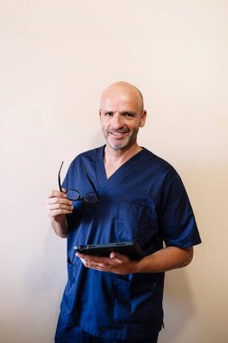 Tablet sağlık görevlisiyle gülümseyen doktorun stüdyo portresi.